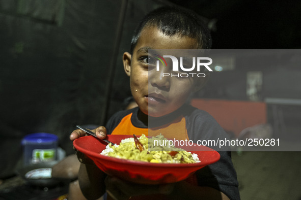 A children eat in a refugee camp at Kabanjahe, North Sumatra, Indonesia, on Sept. 11, 2014. The volcano Mount Sinabung has erupted intermitt...