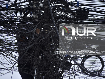 An electrician of Nepal Electricity Authority (NEA) arranging Electric wires at Pulchowk, Patan, Nepal on Tuesday, February 27, 2018. (