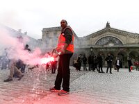 Employee of the French state owned railway company SNCF holds a flare during a demonstration in front of the Gare de l’Est train station on...