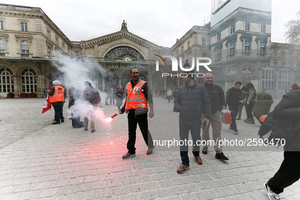 Employee of the French state owned railway company SNCF holds a flare during a demonstration in front of the Gare de l’Est train station on...