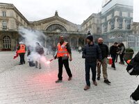 Employee of the French state owned railway company SNCF holds a flare during a demonstration in front of the Gare de l’Est train station on...