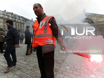 Employee of the French state owned railway company SNCF holds a flare during a demonstration in front of the Gare de l’Est train station on...