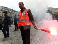 Employee of the French state owned railway company SNCF holds a flare during a demonstration in front of the Gare de l’Est train station on...