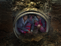 Worker took refuge in an under construction sewerage pipe line while it was raining outside in Dhaka, Bangladesh, on 4 April 2018. (