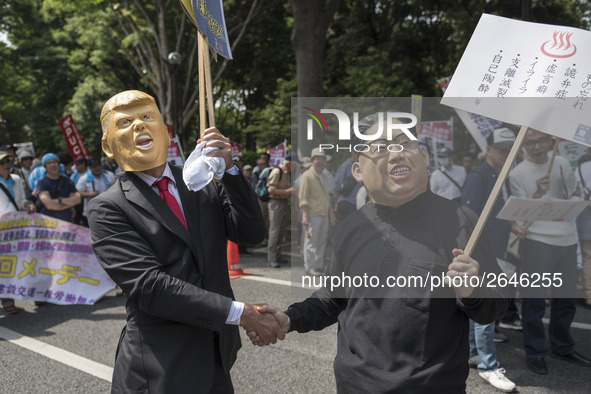 Workers wearing masks to look like US President Donald Trump and North Korean Kim Jong-Un shake hands during the May Day rally sponsored by...