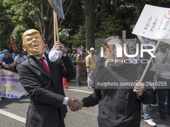 Workers wearing masks to look like US President Donald Trump and North Korean Kim Jong-Un shake hands during the May Day rally sponsored by...