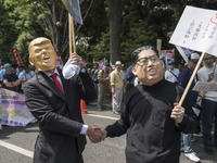 Workers wearing masks to look like US President Donald Trump and North Korean Kim Jong-Un shake hands during the May Day rally sponsored by...