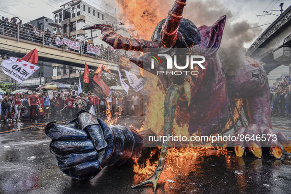 Workers burn an effigy of President Rodrigo Duterte as they take part in labor day demonstrations outside the presidential palace in Manila,...