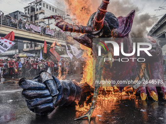 Workers burn an effigy of President Rodrigo Duterte as they take part in labor day demonstrations outside the presidential palace in Manila,...