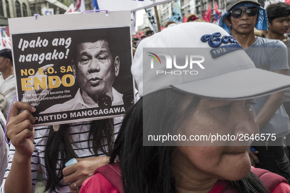 A worker holds a placard with President Rodrigo Duterte's portrait during labor day demonstrations outside the presidential palace in Manila...