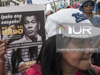 A worker holds a placard with President Rodrigo Duterte's portrait during labor day demonstrations outside the presidential palace in Manila...