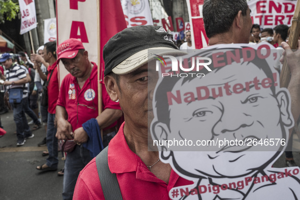 A worker holds a placard with President Rodrigo Duterte's portrait during labor day demonstrations outside the presidential palace in Manila...