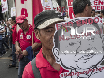 A worker holds a placard with President Rodrigo Duterte's portrait during labor day demonstrations outside the presidential palace in Manila...