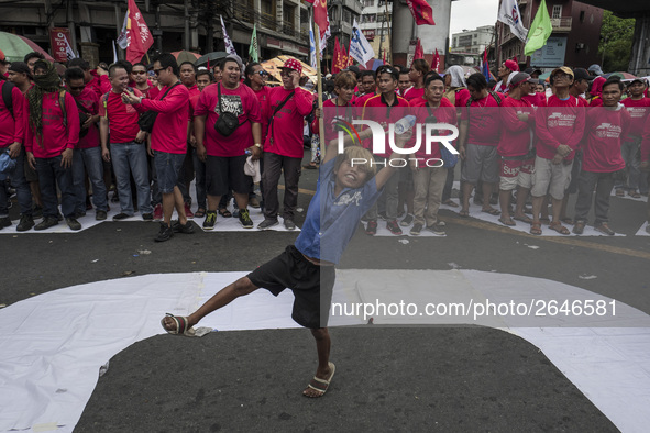 A street child plays while workers take part in labor day demonstrations outside the presidential palace in Manila, Philippines, May 1, 2018...