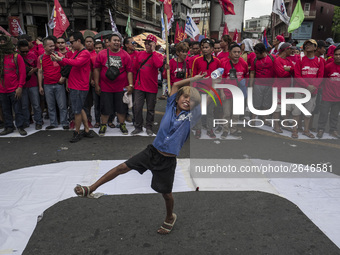 A street child plays while workers take part in labor day demonstrations outside the presidential palace in Manila, Philippines, May 1, 2018...