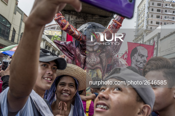 Workers take a selfie with an effigy of President Rodrigo Duterte during labor day demonstrations outside the presidential palace in Manila,...