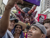 Workers take a selfie with an effigy of President Rodrigo Duterte during labor day demonstrations outside the presidential palace in Manila,...