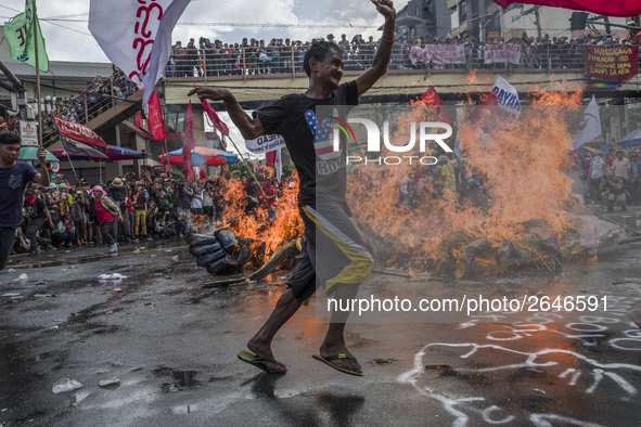 A worker runs past a burning effigy of President Rodrigo Duterte as he takes part in labor day demonstrations outside the presidential palac...