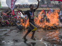 A worker runs past a burning effigy of President Rodrigo Duterte as he takes part in labor day demonstrations outside the presidential palac...