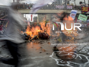 Workers run past a burning effigy of President Rodrigo Duterte as they take part in labor day demonstrations outside the presidential palace...