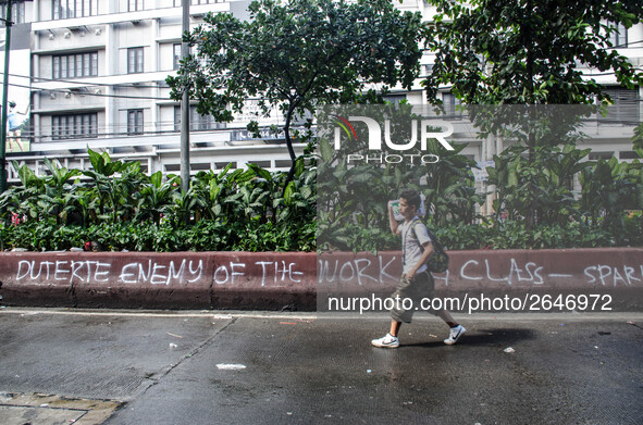 A man walks past a spray-painted slogan saying "Duterte Enemy of the Working Class" after Labor Day Protest ended. Activists gather in Mendi...