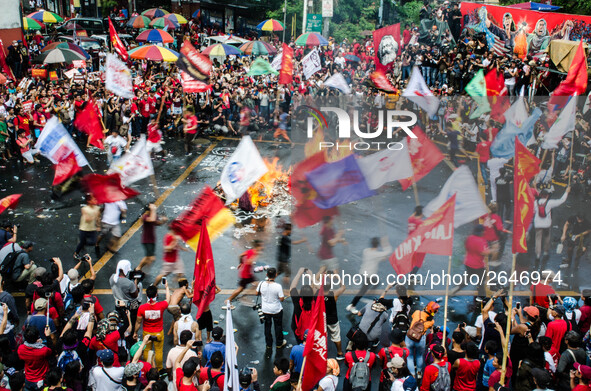 Activists wave flags of different militant groups as they circle the burning effigy of Rodrigo Duterte during the Labor Day Protest in Mendi...