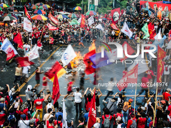 Activists wave flags of different militant groups as they circle the burning effigy of Rodrigo Duterte during the Labor Day Protest in Mendi...