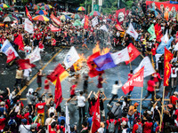 Activists wave flags of different militant groups as they circle the burning effigy of Rodrigo Duterte during the Labor Day Protest in Mendi...