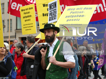 A man with traditional Bavarian clothing has a sign against the Polizeiaufgabengesetz. Several thousands followed the invitation of the trad...