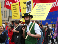 A man with traditional Bavarian clothing has a sign against the Polizeiaufgabengesetz. Several thousands followed the invitation of the trad...