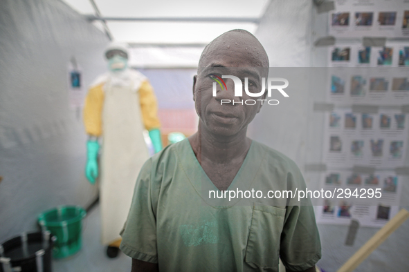 Samuel, a 51-year-old nurse from Monrovia spent one hour in PPE shortly before this photo was taken. The man standing in the background help...