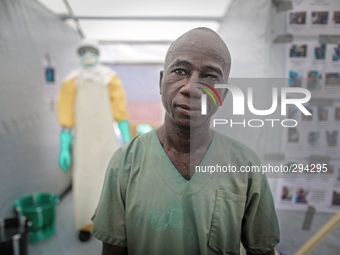 Samuel, a 51-year-old nurse from Monrovia spent one hour in PPE shortly before this photo was taken. The man standing in the background help...