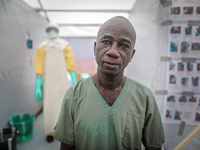 Samuel, a 51-year-old nurse from Monrovia spent one hour in PPE shortly before this photo was taken. The man standing in the background help...