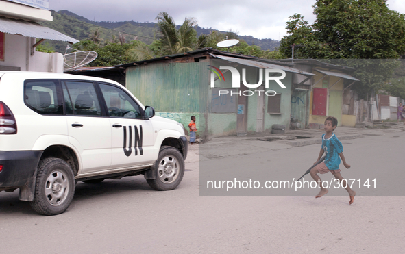 Young Timorese boy run towards a UN vehicle with a toy gun. 