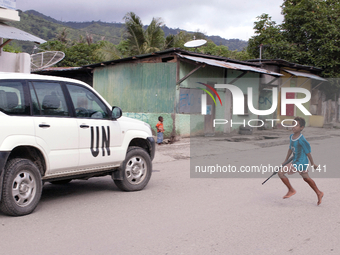 Young Timorese boy run towards a UN vehicle with a toy gun. (