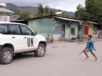 Young Timorese boy run towards a UN vehicle with a toy gun. (