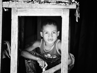 Timorese boy hiding under a table to escape Timor Leste's searing heat. (