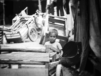 A young child playing with carts at a Dili market. (