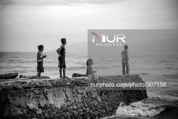 Young children fishing over a drain at Dili Beach 