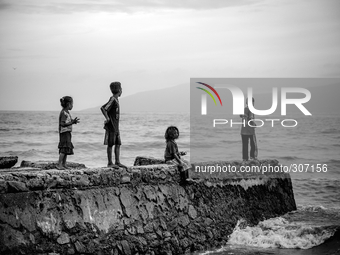 Young children fishing over a drain at Dili Beach (