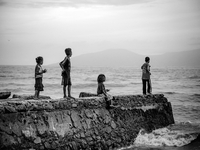 Young children fishing over a drain at Dili Beach (