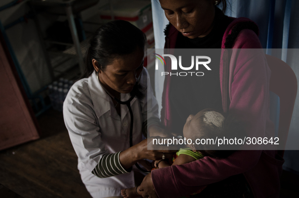 Phumi, Moat Khla, Tonle Sap, Cambodia. Dr Sopheak Phin attends to a unwell infant. Traditional remedies and beliefs are still very much prev...