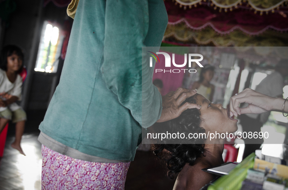 Phumi Stoeng Chrou, Tonle Sap, Cambodia. A child is given a vitamin A tablet at the village chiefs house that is used as a make shift clinic...