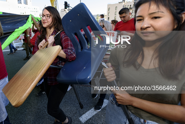 Supporters of public education carry a school desk and chair during the March for Public Education in Los Angeles, California on December 15...