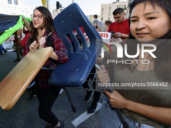 Supporters of public education carry a school desk and chair during the March for Public Education in Los Angeles, California on December 15...