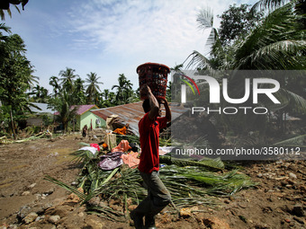 A man collects debris from a house damaged after a flood caused by damage to a river embankment after heavy rains in North Aceh, on November...