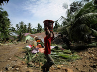 A man collects debris from a house damaged after a flood caused by damage to a river embankment after heavy rains in North Aceh, on November...