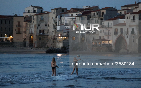 Children play with a ball on the waterfront at sunset in Cefalu. Sicily, Italy, Saturday, May 5, 2018
 