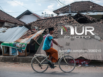 Cyclists pass through the ruins of houses due to earthquake on August 10, 2018 in Pamenang, North Lombok Regency, Indonesia. (