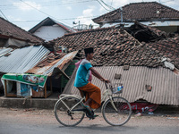 Cyclists pass through the ruins of houses due to earthquake on August 10, 2018 in Pamenang, North Lombok Regency, Indonesia. (